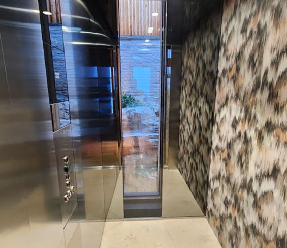 Ge&ouml;ffnete Aufzugskabine mit gemusterter Wand im Projekt Bellevue in Aurach.